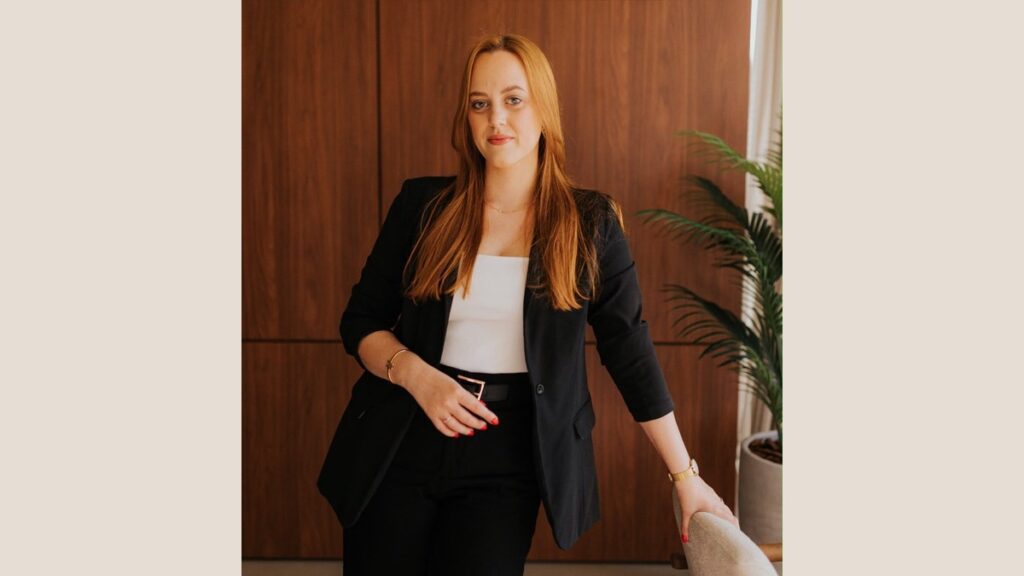Encontro gratuito em Novo Hamburgo aborda vendas sem depender de descontos Izabela Pessi, palestrante do encontro sobre vendas em Novo Hamburgo, diante de uma parede de madeira.