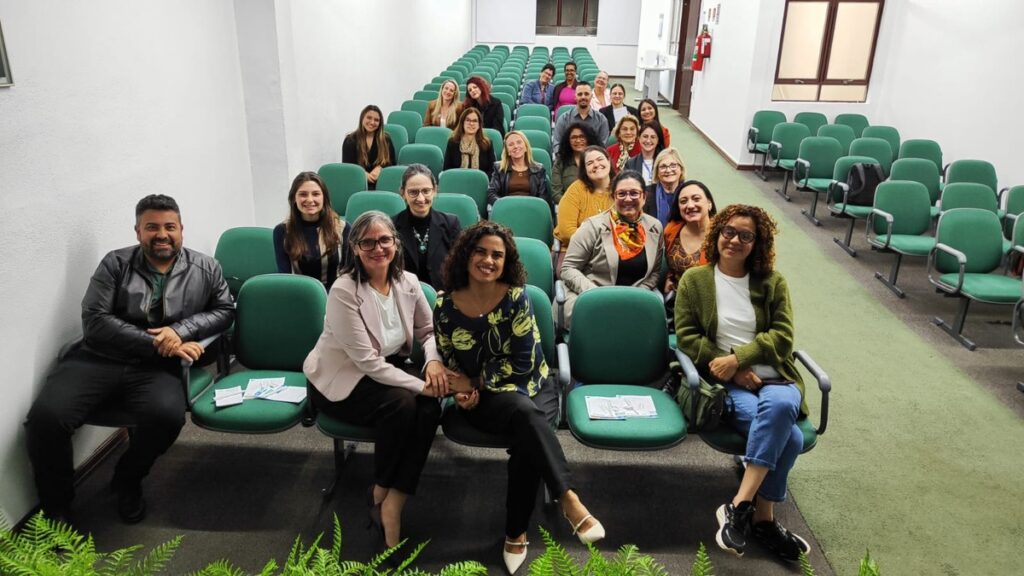 Participantes do Crescer Juntos reunidos em auditório com cadeiras verdes